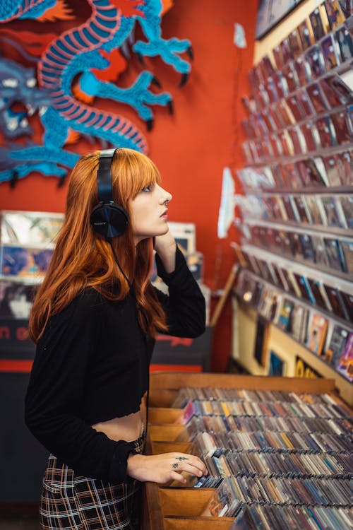blunt cut red hair girl listening to music at music store
