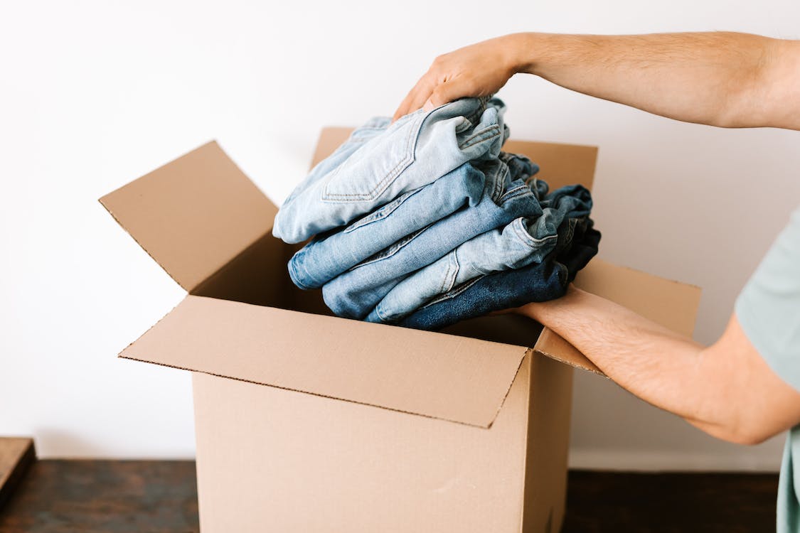 A man putting jeans into a box.