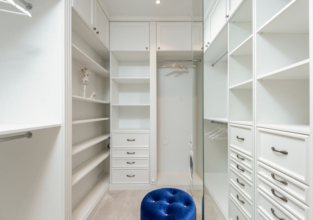A white built-in closet with lots of drawers and shelves.