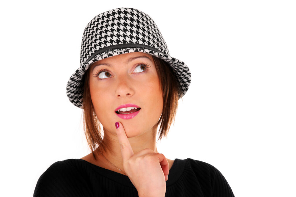 A picture of a young woman in a houndstooth black & white plaid hat smiling over white background