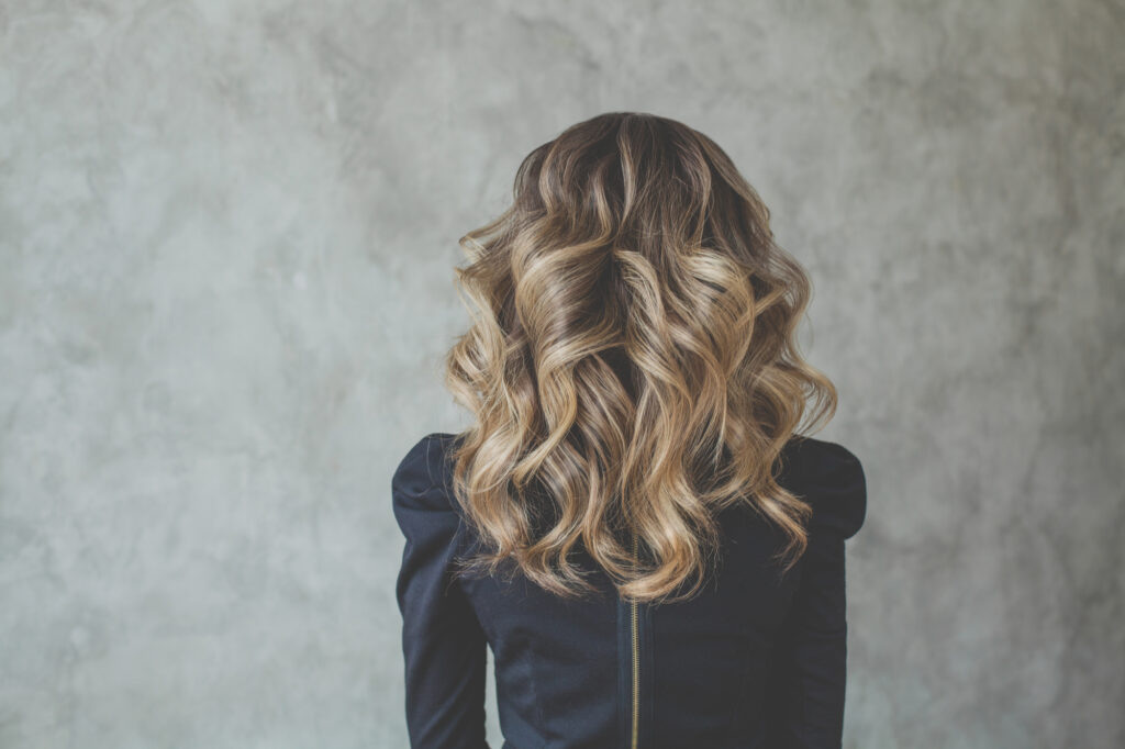 Curly Balayage hair. Perfect woman back and head with curly hairdo
