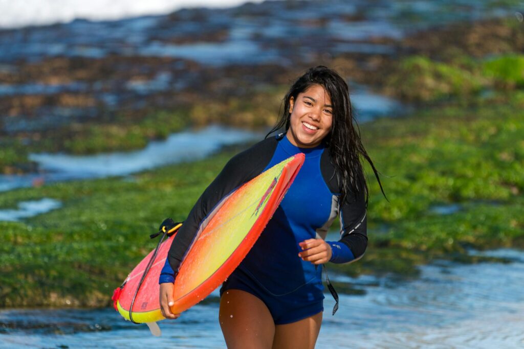 A woman carrying a surfboard.