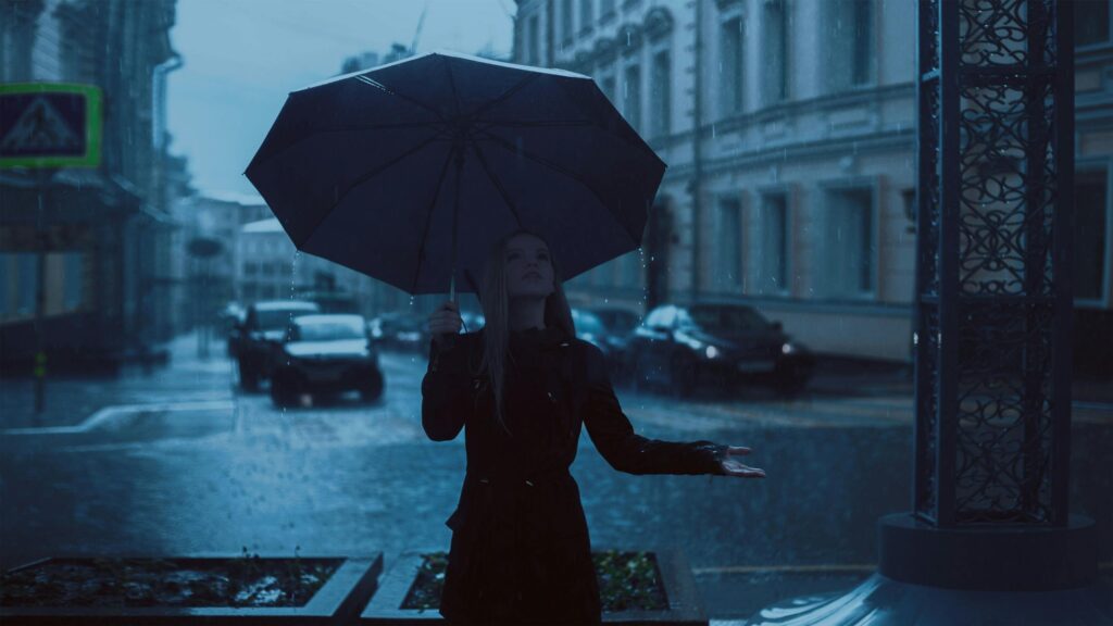 A woman standing in the rain holding an umbrella after learning all the seasonal fashion tips for Seattle.