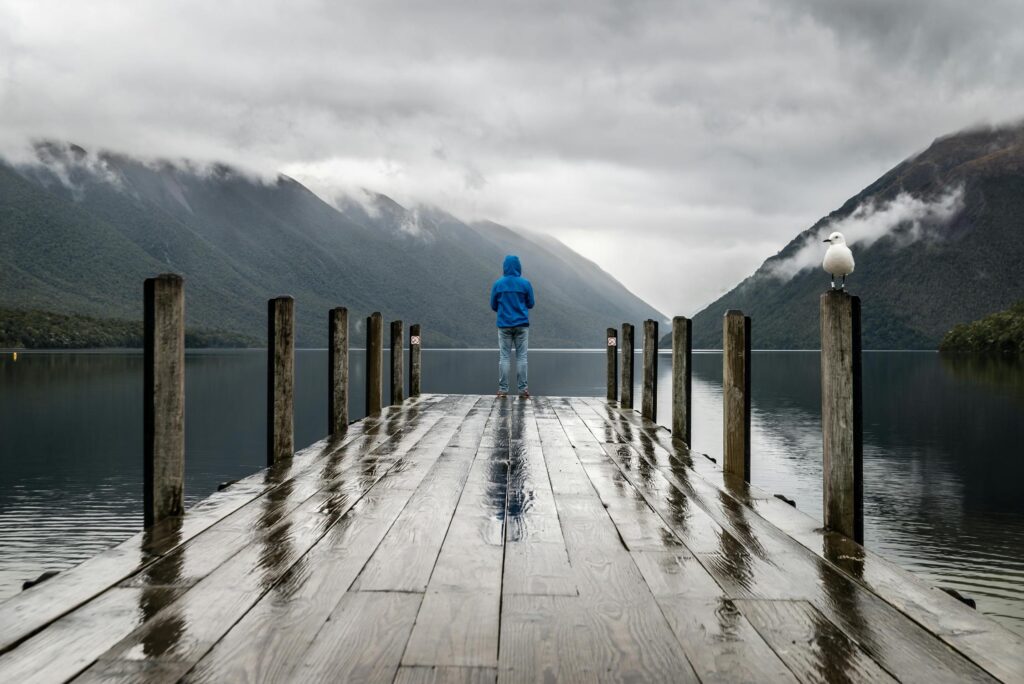 A person standing on a dock in the rain.