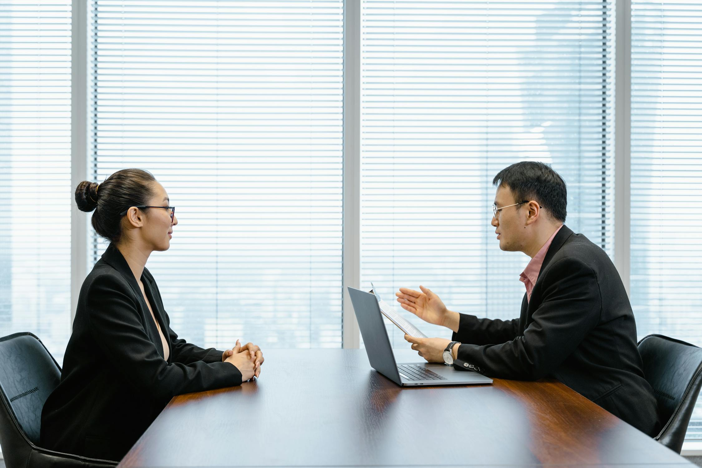 Formally dressed man and woman sitting by the table in the office