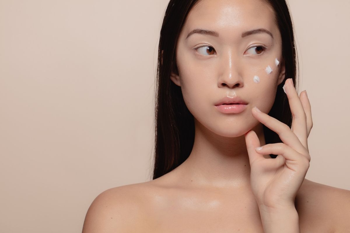 Woman applying K-beauty skincare cream to her face as part of a multi-step routine
